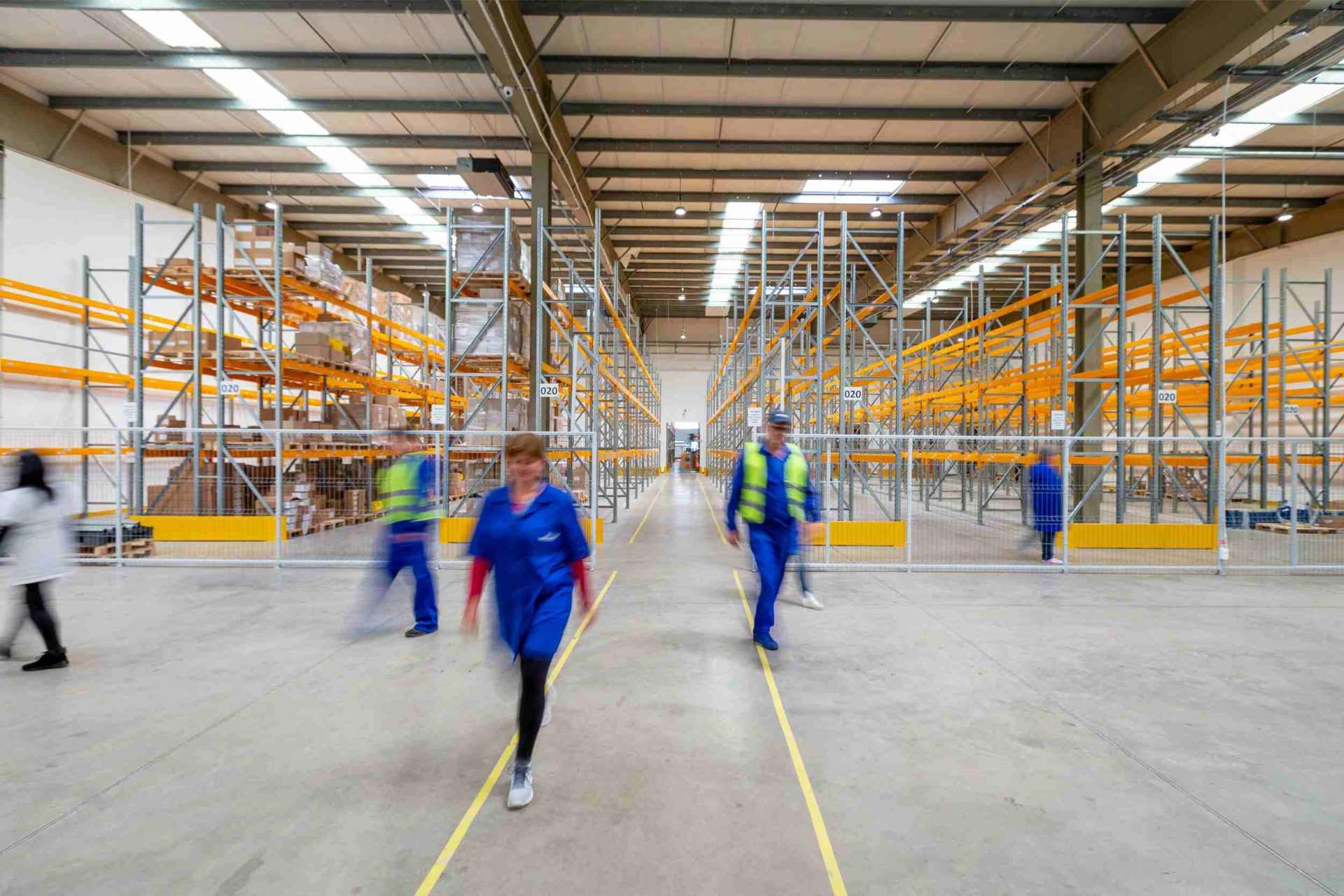 Warehouse with workers walking between empty shelves