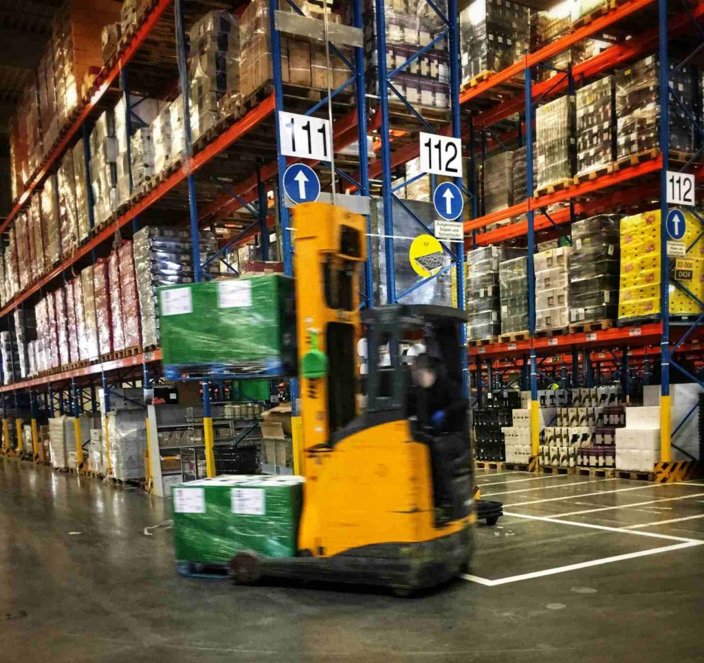 Forklift moving green-wrapped pallets in warehouse